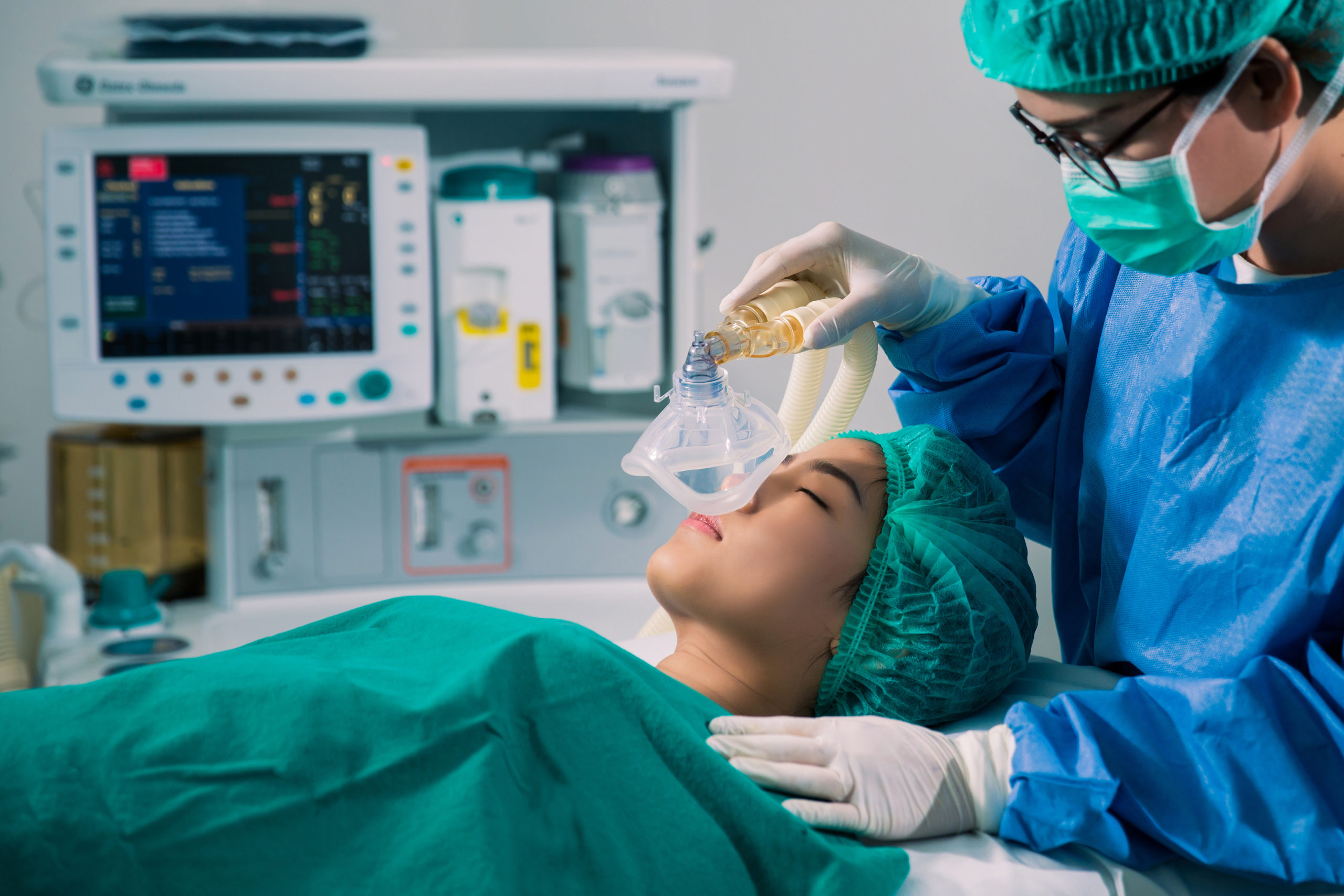 Image of surgeon prepping a patient for surgery in operating room with oxygen mask
